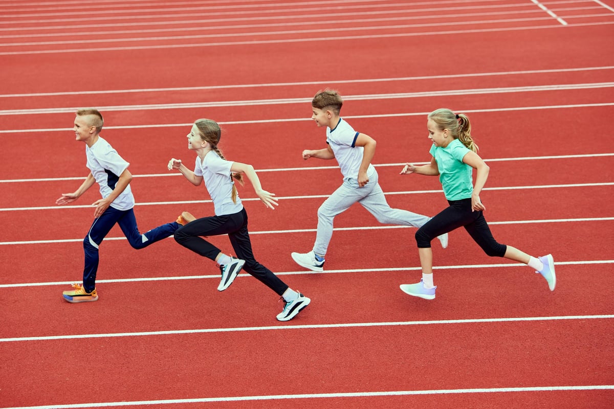 Group of children running on treadmill at the stadium. Little fit boys and girls in sportswear training as athletes outdoor